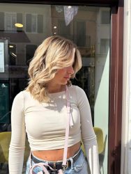 Femme blonde devant un salon de coiffure