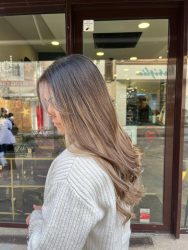 Femme posant devant un salon de coiffure